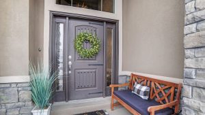 The front entry area of a home with a bench outside and a beautiful glass-detailed entry door