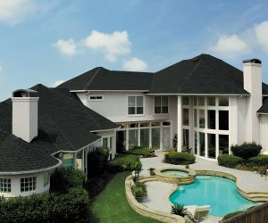Exterior of a home with a gray shingle roof and a pool in the backyard